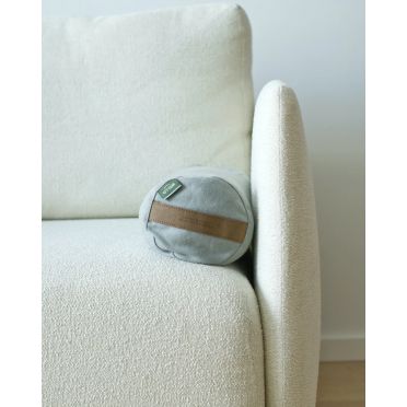 Jasnoniebieski mały wałek gryczany z uchwytem z wegańskiej skóry z celulozy, ułożony na jasnej, miękkiej sofie o obłym kształcie.